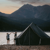 10 regatta bell tent night sky in front of a lake with two women cheering with their drinks