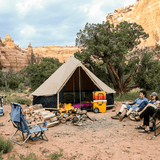 Regatta 360 tent set up near a rocky area with a couple sitting in front of it and a bonfire next to it