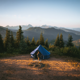 Regatta bell tent sapphire blue in forest with man walking into it