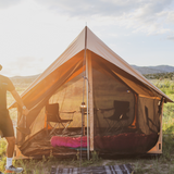 Rover scout tent placed outdoors in the sunlight with mesh partially open and shows 2 chairs and a table placed inside with a lantern