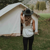 alpha wall tent placed outside with a girl wearing a hat facing it