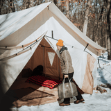 alpha wall tent set up in the snow with a man going inside it