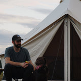 avalon bell tent with a man and his dog sitting in front of it