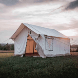 white canvas wall tent set up in a grassy field