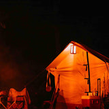 alpha wall tent at night time glowing in the light of a lantern