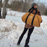 Hoplite Canvas Parachute Bag tan color with a girl holding it in the snow storm.